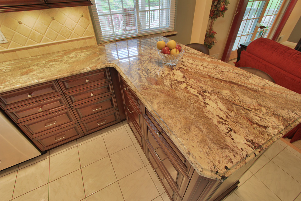 Inspiration for a mid-sized l-shaped ceramic tile eat-in kitchen remodel with a double-bowl sink, dark wood cabinets, granite countertops, beige backsplash, stone tile backsplash, stainless steel appliances and no island