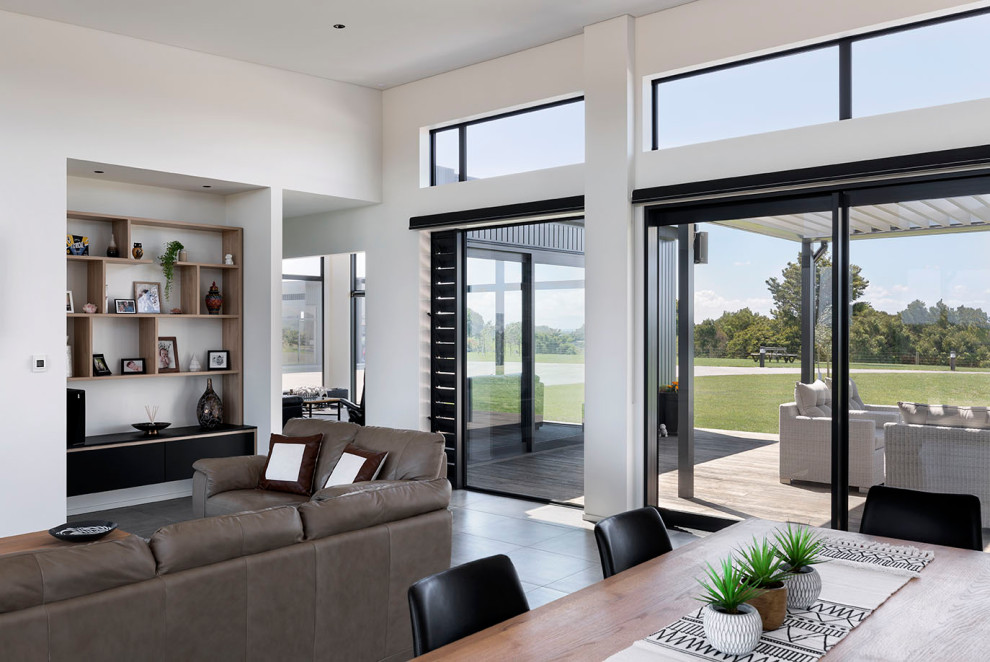 This is an example of a large contemporary open plan living room in Auckland with white walls, ceramic flooring and grey floors.