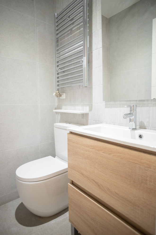 Inspiration for a medium sized mediterranean ensuite bathroom in Barcelona with flat-panel cabinets, medium wood cabinets, a built-in shower, a one-piece toilet, grey tiles, ceramic tiles, ceramic flooring, a trough sink, grey floors, a hinged door, white worktops, an enclosed toilet, a single sink and a floating vanity unit.