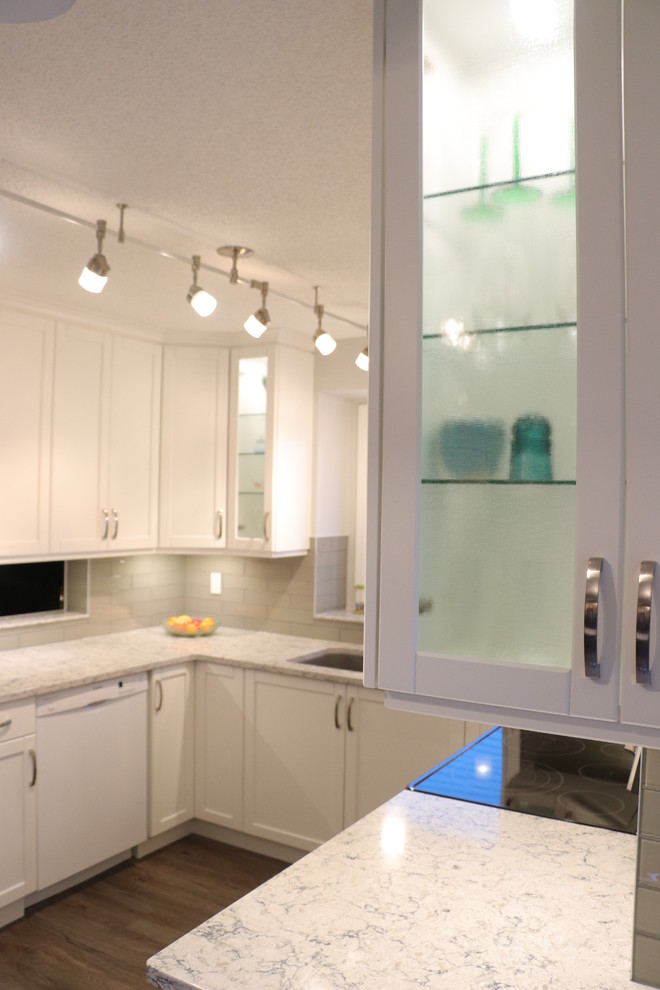 Example of a small transitional u-shaped eat-in kitchen design in Edmonton with an undermount sink, recessed-panel cabinets, white cabinets, quartz countertops, gray backsplash, glass tile backsplash, stainless steel appliances, no island and white countertops