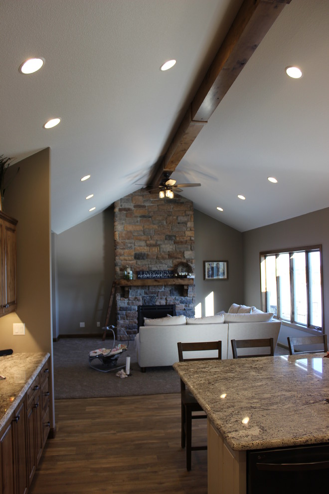 Inspiration for a large rustic l-shaped medium tone wood floor and brown floor open concept kitchen remodel with an undermount sink, raised-panel cabinets, medium tone wood cabinets, granite countertops, stainless steel appliances and an island