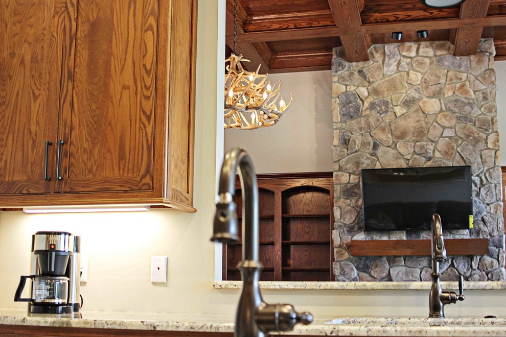 Example of a mountain style kitchen design with dark wood cabinets, granite countertops and an island