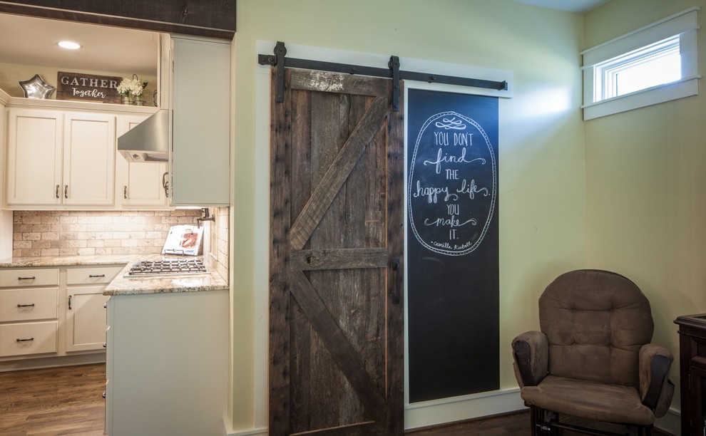 Example of a mid-sized transitional u-shaped dark wood floor and brown floor eat-in kitchen design with a farmhouse sink, recessed-panel cabinets, white cabinets, granite countertops, beige backsplash, ceramic backsplash, stainless steel appliances and an island