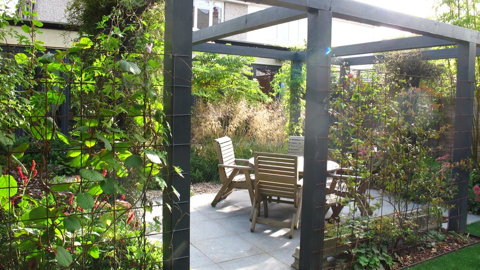 Design ideas for a mid-sized contemporary backyard patio in London with a vertical garden and natural stone pavers.