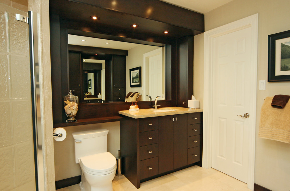 This is an example of a mid-sized contemporary master bathroom in Toronto with dark wood cabinets, a corner shower, a two-piece toilet, beige walls, porcelain floors, an undermount sink, flat-panel cabinets and limestone benchtops.