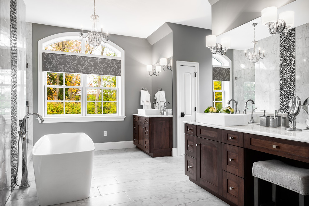 Design ideas for a traditional master bathroom in Philadelphia with recessed-panel cabinets, dark wood cabinets, marble benchtops, a freestanding tub, an open shower, white tile, stone tile, grey walls and marble floors.