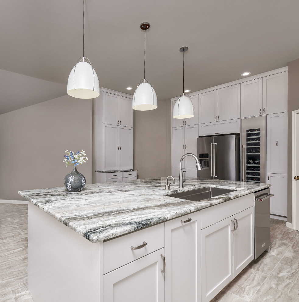 Example of a transitional porcelain tile and gray floor kitchen pantry design with a triple-bowl sink, shaker cabinets, white cabinets, quartzite countertops, blue backsplash, glass tile backsplash, stainless steel appliances, an island and gray countertops