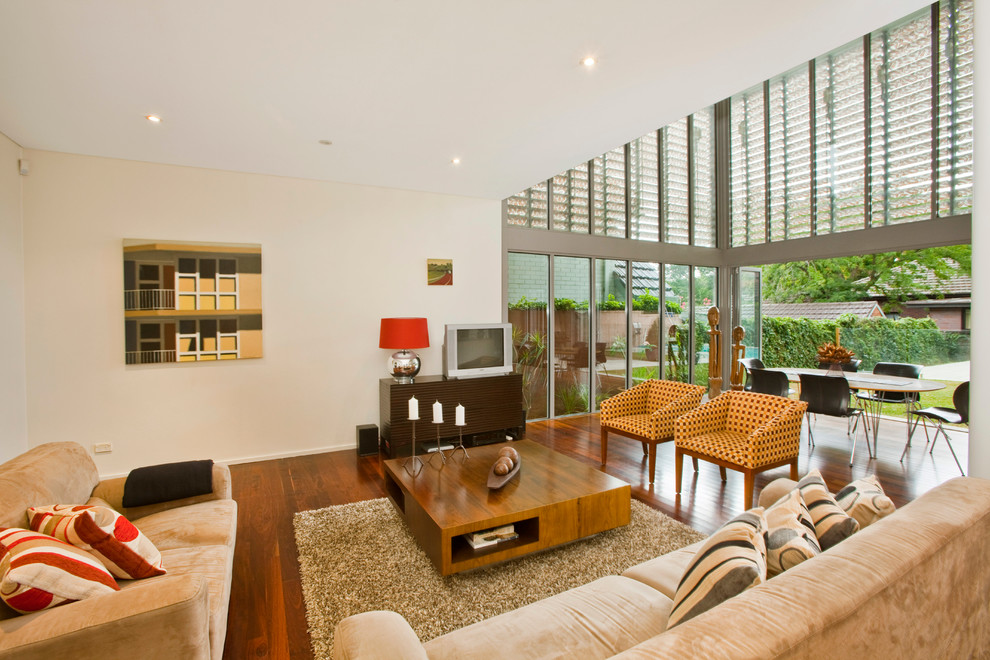 Photo of a contemporary formal open concept living room in Sydney with white walls, medium hardwood floors and a freestanding tv.