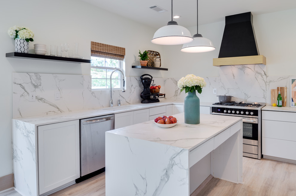 Design ideas for a mid-sized transitional l-shaped separate kitchen in Orange County with an undermount sink, shaker cabinets, white cabinets, marble benchtops, white splashback, stone slab splashback, stainless steel appliances, light hardwood floors, with island and beige floor.