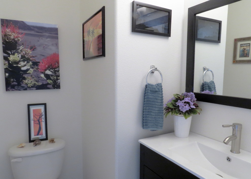 Small transitional medium tone wood floor bathroom photo with flat-panel cabinets, dark wood cabinets, a two-piece toilet, white walls, an integrated sink and quartz countertops