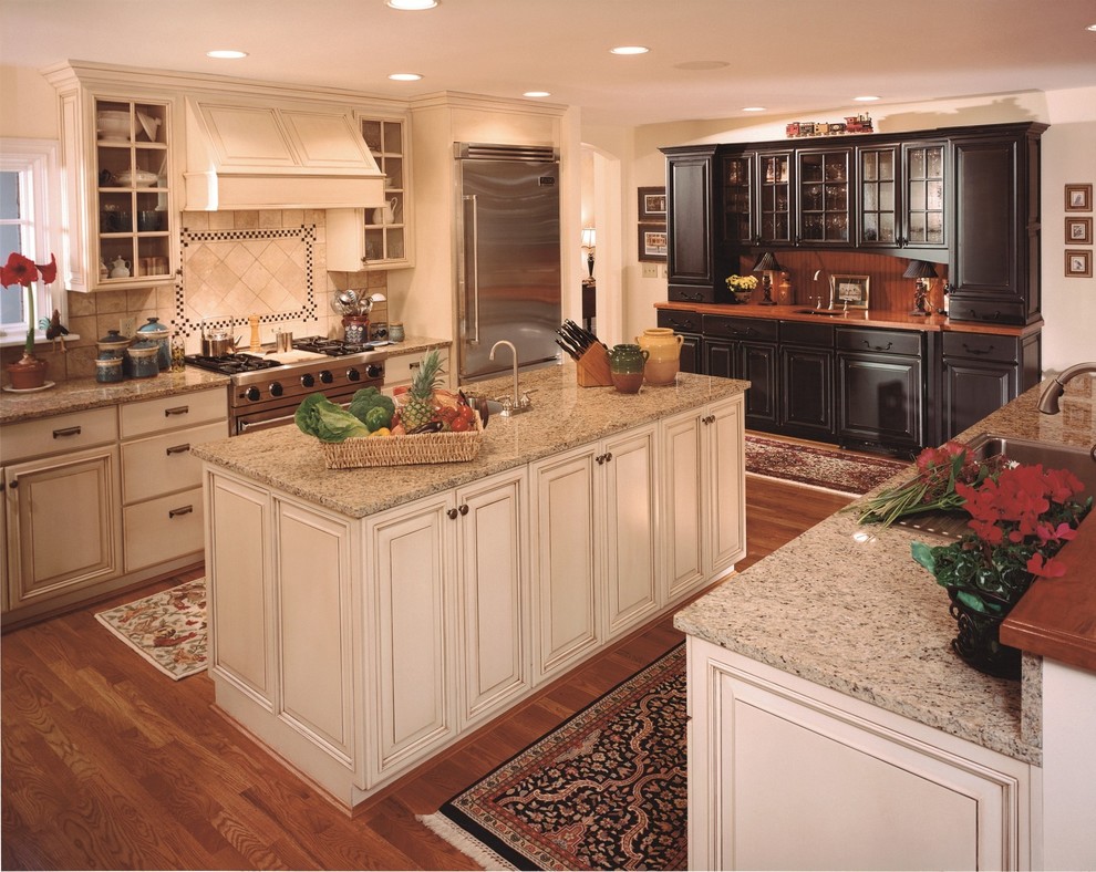 Photo of a mid-sized country u-shaped separate kitchen in New York with a drop-in sink, raised-panel cabinets, white cabinets, granite benchtops, beige splashback, ceramic splashback, stainless steel appliances, dark hardwood floors and with island.