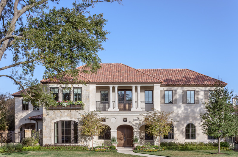 This is an example of a large mediterranean two-storey beige exterior in Houston with stone veneer and a hip roof.