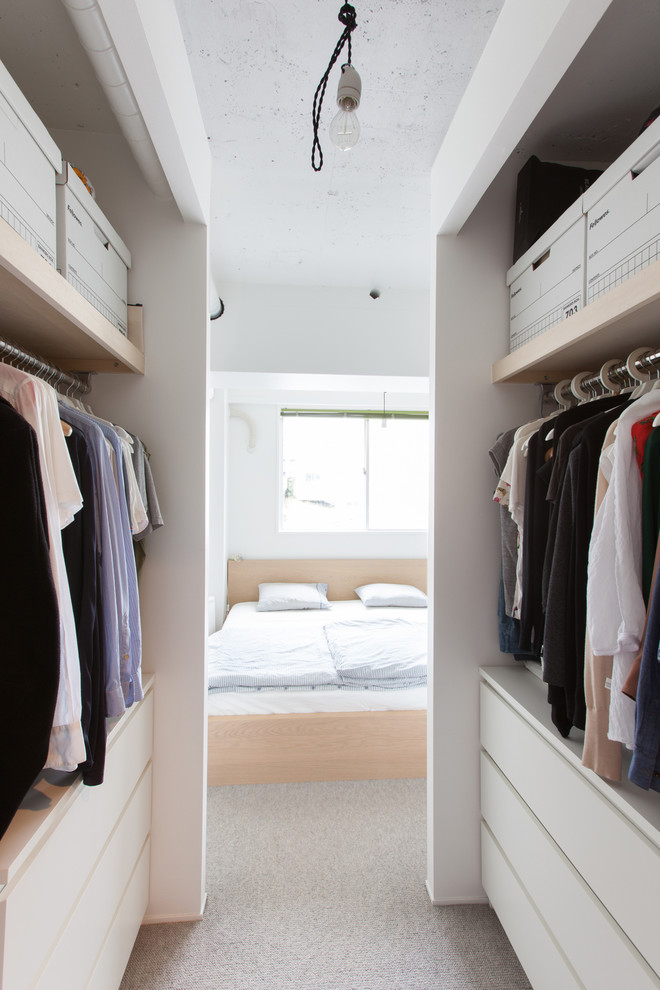 This is an example of a contemporary gender-neutral walk-in wardrobe in Tokyo with open cabinets, white cabinets, carpet and grey floor.