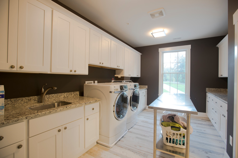Large transitional galley dedicated laundry room in Baltimore with an undermount sink, shaker cabinets, white cabinets, granite benchtops, brown walls, light hardwood floors, a side-by-side washer and dryer, beige floor and multi-coloured benchtop.