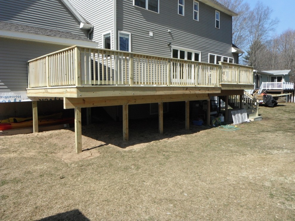 Elegant backyard outdoor kitchen deck photo with a roof extension
