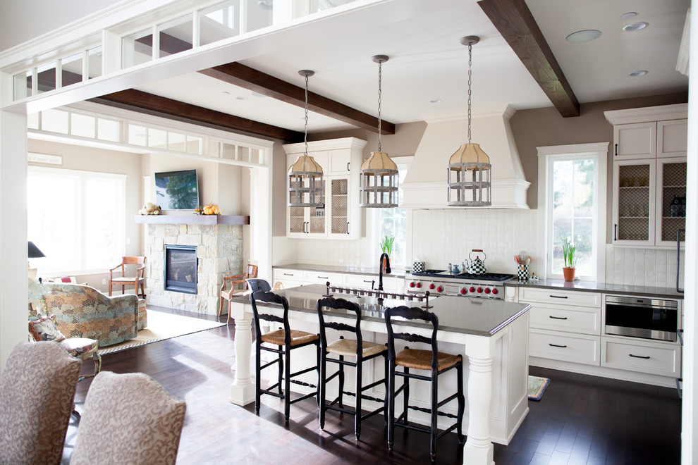 Inspiration for a large country l-shaped open plan kitchen in Seattle with shaker cabinets, white cabinets, white splashback, ceramic splashback, stainless steel appliances, dark hardwood floors, with island, brown floor, a farmhouse sink and granite benchtops.
