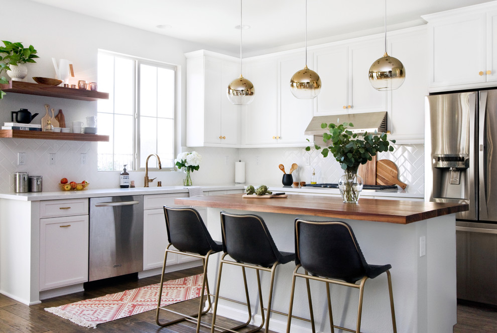 Design ideas for a transitional l-shaped kitchen in San Diego with a single-bowl sink, white cabinets, quartz benchtops, white splashback, subway tile splashback, stainless steel appliances, with island and dark hardwood floors.
