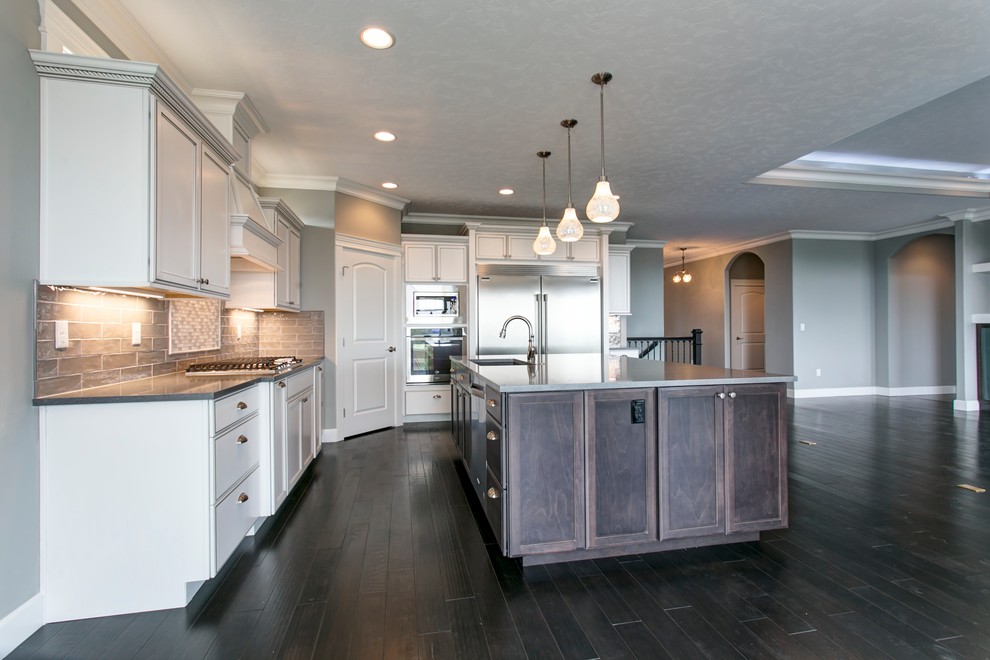 Example of a mid-sized transitional l-shaped dark wood floor open concept kitchen design in Seattle with shaker cabinets, white cabinets, quartz countertops, gray backsplash, an island, an undermount sink, glass tile backsplash and stainless steel appliances