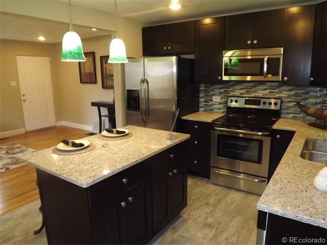 Example of a mid-sized transitional l-shaped eat-in kitchen design in Denver with an undermount sink, shaker cabinets, granite countertops, stainless steel appliances, an island, black cabinets, blue backsplash and ceramic backsplash