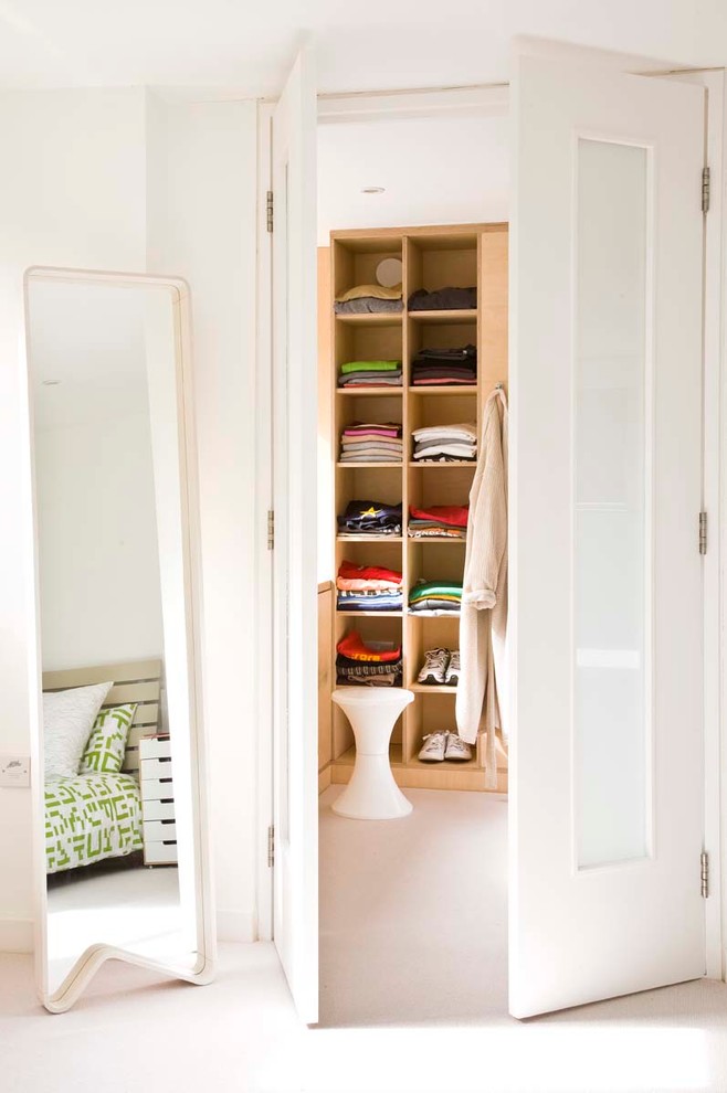 Photo of a small contemporary gender-neutral walk-in wardrobe in Surrey with open cabinets, light wood cabinets and carpet.