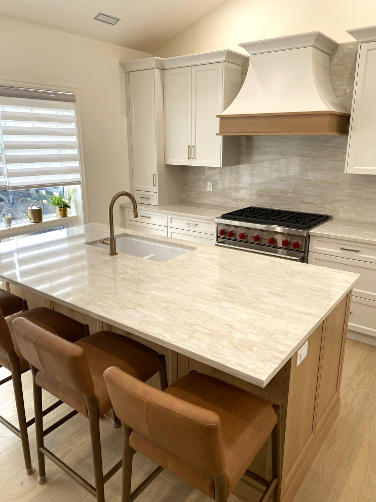 Example of a small transitional galley light wood floor and vaulted ceiling open concept kitchen design in Toronto with an undermount sink, recessed-panel cabinets, white cabinets, quartz countertops, quartz backsplash and stainless steel appliances