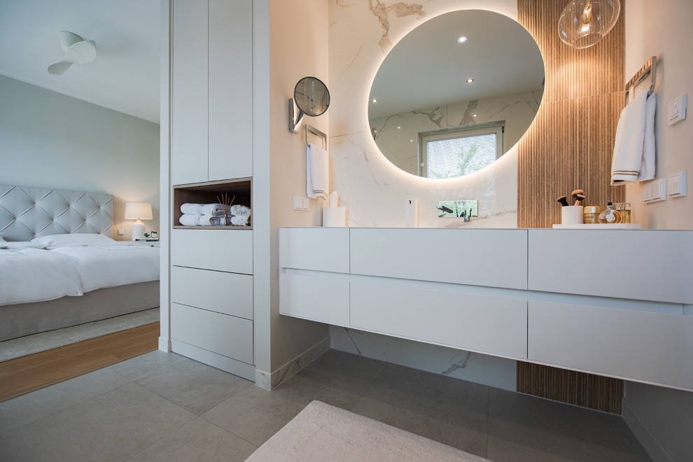 This is an example of a mid-sized contemporary master bathroom with flat-panel cabinets, white cabinets, a curbless shower, a wall-mount toilet, beige tile, ceramic tile, beige walls, ceramic floors, an integrated sink, solid surface benchtops, grey floor, white benchtops, a single vanity and a built-in vanity.