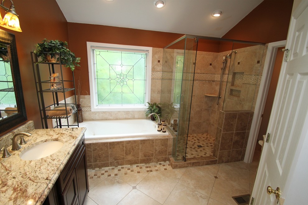 Inspiration for a mid-sized traditional master bathroom in Cincinnati with an undermount sink, recessed-panel cabinets, dark wood cabinets, granite benchtops, a corner shower, a one-piece toilet, beige tile, stone tile, red walls, travertine floors, a drop-in tub, beige floor, a hinged shower door and multi-coloured benchtops.