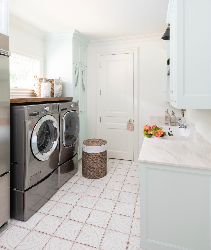 Mid-sized transitional l-shaped terra-cotta tile and multicolored floor utility room photo in Austin with an utility sink, raised-panel cabinets, blue cabinets, quartzite countertops, white walls, a side-by-side washer/dryer and beige countertops