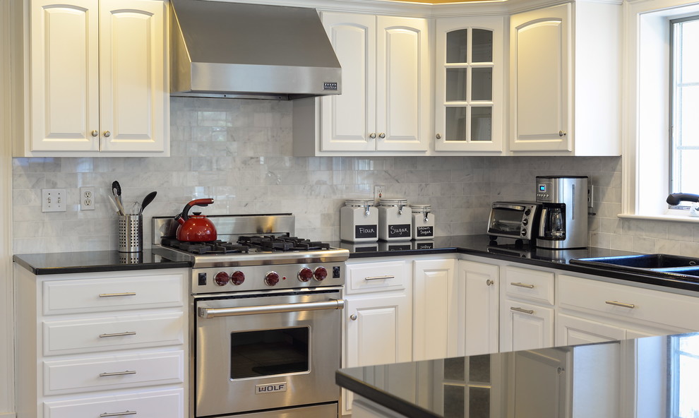 Mid-sized transitional l-shaped kitchen photo in Boston with raised-panel cabinets, white cabinets, granite countertops, marble backsplash, stainless steel appliances and black countertops