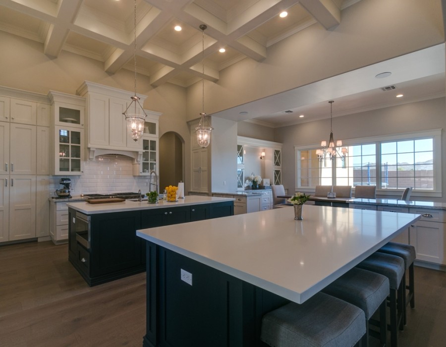 Example of a large transitional l-shaped dark wood floor and brown floor open concept kitchen design in Phoenix with an undermount sink, shaker cabinets, white cabinets, quartz countertops, white backsplash, subway tile backsplash, stainless steel appliances and two islands