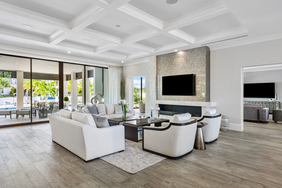 Inspiration for a large traditional open plan living room in Miami with a home bar, white walls, light hardwood flooring, a ribbon fireplace, a wooden fireplace surround, a freestanding tv, beige floors, a coffered ceiling and wallpapered walls.