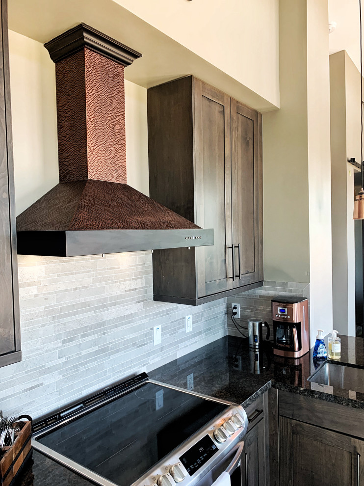 Photo of a small contemporary l-shaped open plan kitchen in Phoenix with an undermount sink, shaker cabinets, dark wood cabinets, granite benchtops, grey splashback, limestone splashback, stainless steel appliances, concrete floors, no island, grey floor and black benchtop.