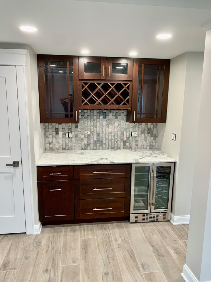 This is an example of a small traditional galley kitchen pantry in Chicago with glass-front cabinets, dark wood cabinets, quartz benchtops, grey splashback, granite splashback, stainless steel appliances, porcelain floors, beige floor and grey benchtop.