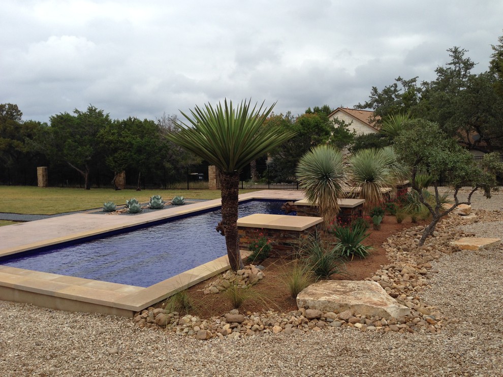 Photo of a mid-sized mediterranean backyard rectangular lap pool in Austin with a water feature and tile.