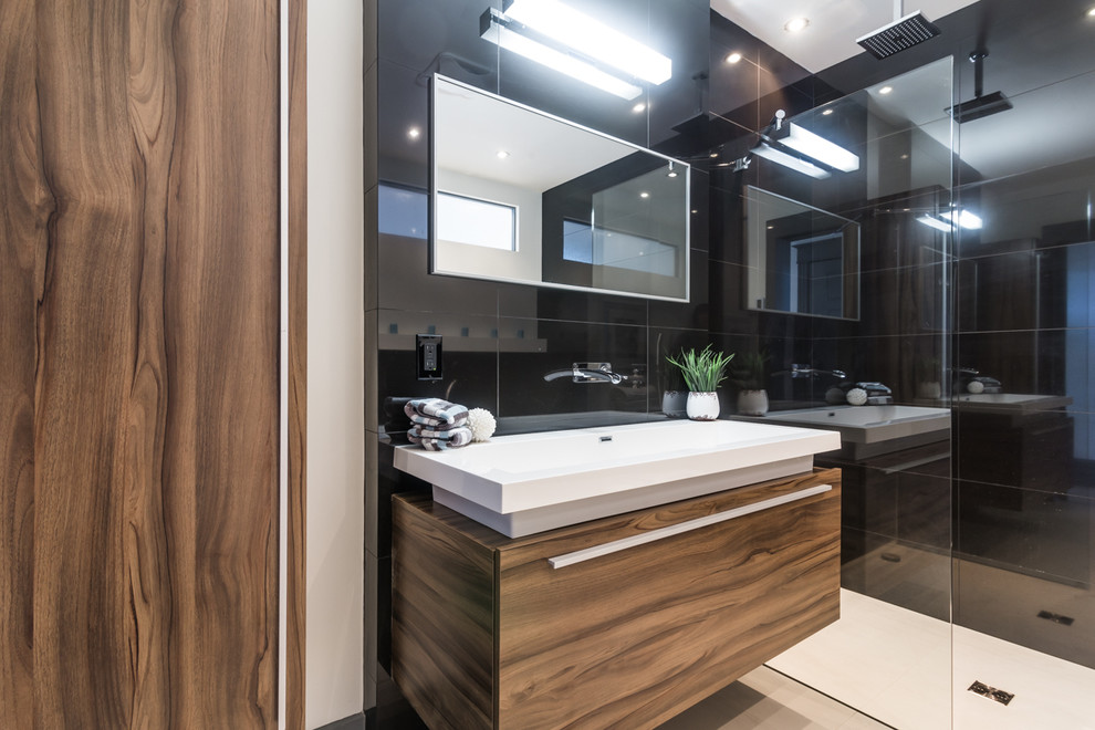 Mid-sized modern master bathroom in Montreal with a trough sink, flat-panel cabinets, light wood cabinets, engineered quartz benchtops, a freestanding tub, a curbless shower, a one-piece toilet, black tile, porcelain tile, white walls and porcelain floors.