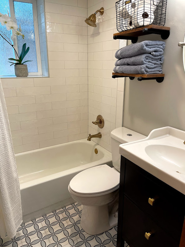 Small transitional bathroom in Portland with shaker cabinets, dark wood cabinets, a drop-in tub, a shower/bathtub combo, a two-piece toilet, white tile, ceramic tile, grey walls, porcelain floors, an integrated sink, multi-coloured floor, a shower curtain, white benchtops, a single vanity and a freestanding vanity.