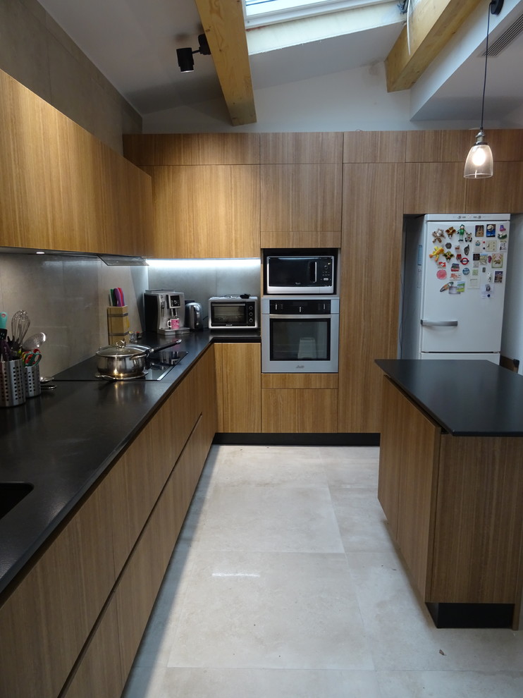 Inspiration for a mid-sized tropical l-shaped eat-in kitchen in Marseille with an integrated sink, beaded inset cabinets, brown cabinets, granite benchtops, beige splashback, ceramic splashback, stainless steel appliances, ceramic floors, with island, beige floor and black benchtop.