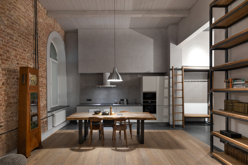 Design ideas for an industrial single-wall open plan kitchen in Moscow with flat-panel cabinets, white cabinets, grey splashback, black appliances, no island, grey floor and grey benchtop.