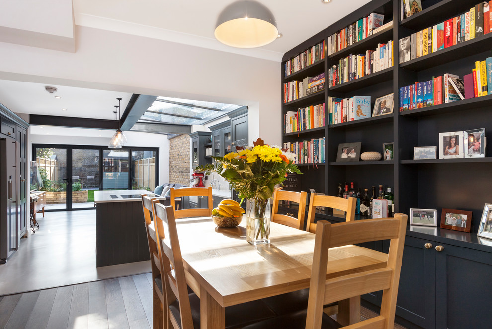This is an example of a transitional open plan dining in London with white walls and brown floor.