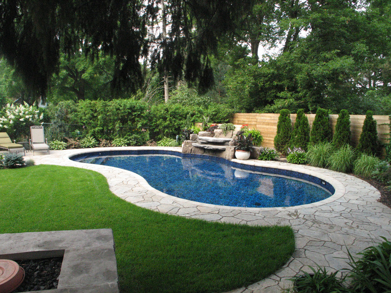This is an example of a mid-sized transitional backyard custom-shaped pool in Toronto with natural stone pavers.