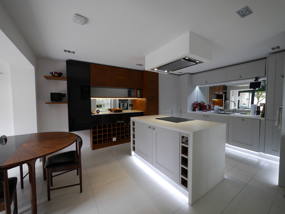 Photo of a mid-sized contemporary u-shaped eat-in kitchen in London with an undermount sink, shaker cabinets, medium wood cabinets, quartzite benchtops, metallic splashback, mirror splashback, stainless steel appliances, ceramic floors, with island, white floor and white benchtop.
