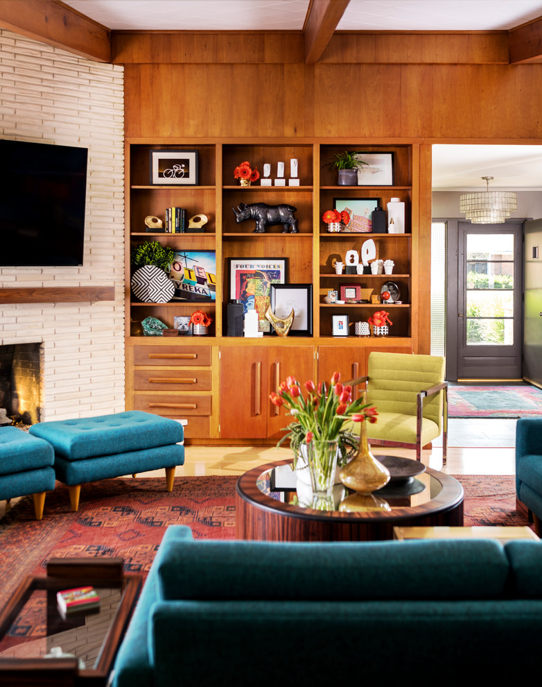 Photo of a large midcentury enclosed living room in Other with brown walls, light hardwood floors, a standard fireplace, a brick fireplace surround, a wall-mounted tv and yellow floor.