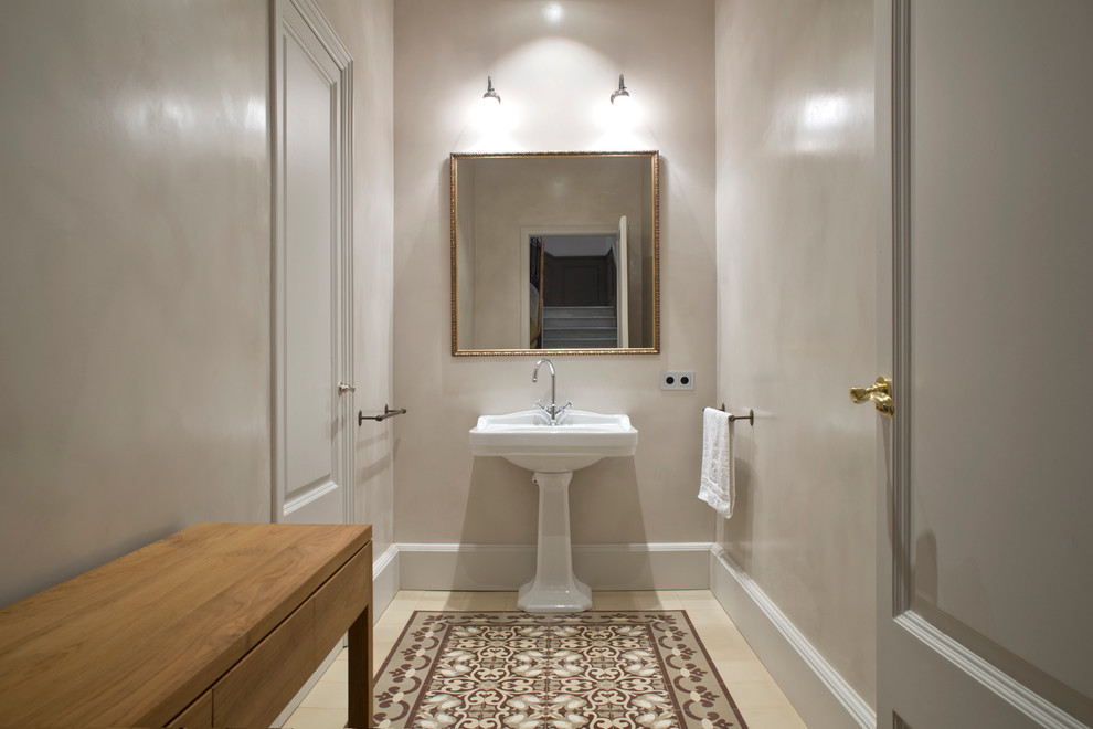 This is an example of a small traditional powder room in Barcelona with furniture-like cabinets, medium wood cabinets, beige walls, ceramic floors and a pedestal sink.