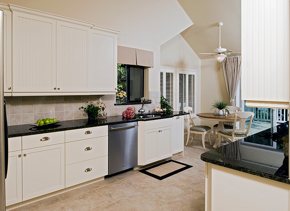Example of a mid-sized transitional galley porcelain tile eat-in kitchen design with shaker cabinets, white cabinets, granite countertops, beige backsplash, porcelain backsplash and stainless steel appliances