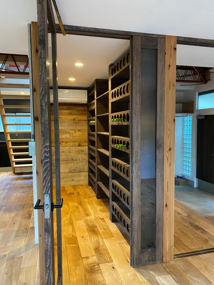 Small industrial wine cellar in Other with medium hardwood floors and storage racks.