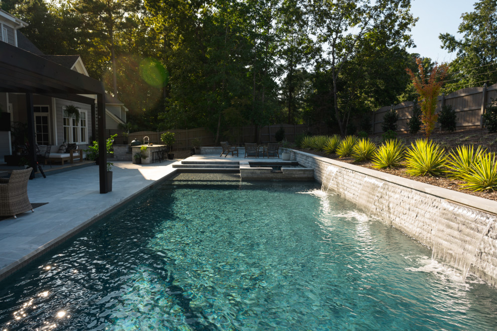 Foto di una piscina monocorsia contemporanea rettangolare di medie dimensioni e dietro casa con una vasca idromassaggio e pavimentazioni in pietra naturale