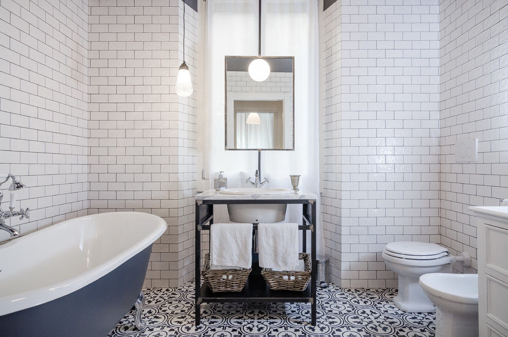 Inspiration for an industrial bathroom in Milan with a claw-foot tub, white tile, subway tile, a console sink, a one-piece toilet, recessed-panel cabinets and white cabinets.