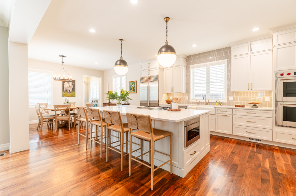 Open concept kitchen - large transitional l-shaped dark wood floor and brown floor open concept kitchen idea in Denver with a farmhouse sink, shaker cabinets, beige cabinets, quartz countertops, beige backsplash, ceramic backsplash, stainless steel appliances, an island and white countertops