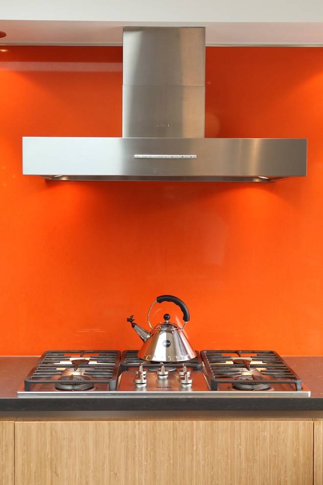 Mid-sized midcentury u-shaped eat-in kitchen in Vancouver with an undermount sink, flat-panel cabinets, light wood cabinets, concrete benchtops, orange splashback, glass sheet splashback, stainless steel appliances, ceramic floors, a peninsula and grey floor.