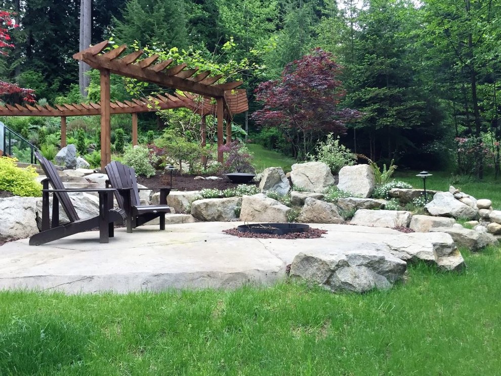 Inspiration for a large country backyard patio in Vancouver with a fire feature, natural stone pavers and a pergola.
